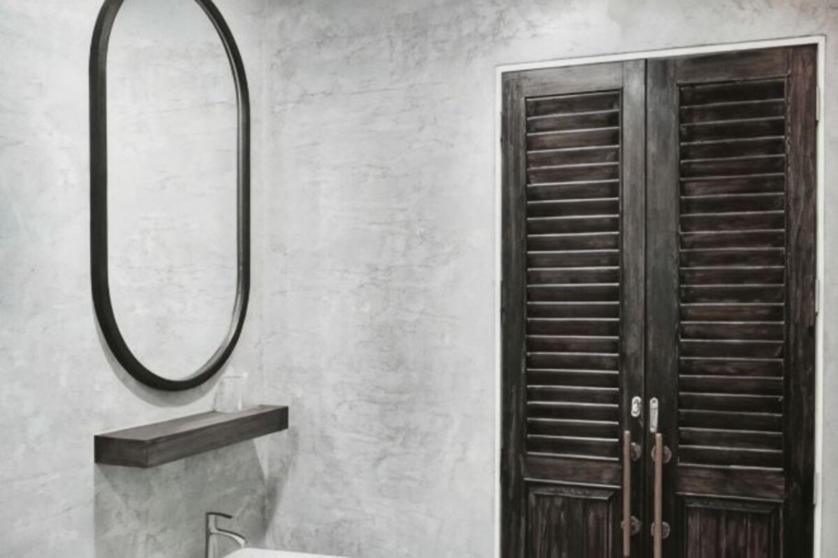 A bathroom with a mirror, a sink, and a wooden door.