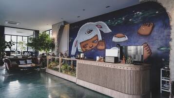 A modern reception area with a large mural, a reception desk, seating area, and a view of the outdoors.