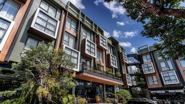 A modern building with large windows, a balcony with plants, and a sign that reads "The World’s Best Hotel". - The Wood (Surin)