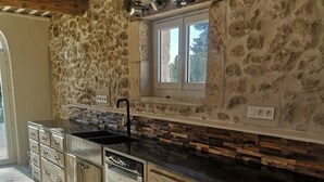 Una cocina con paredes de piedra, una ventana y lavavajillas empotrado.