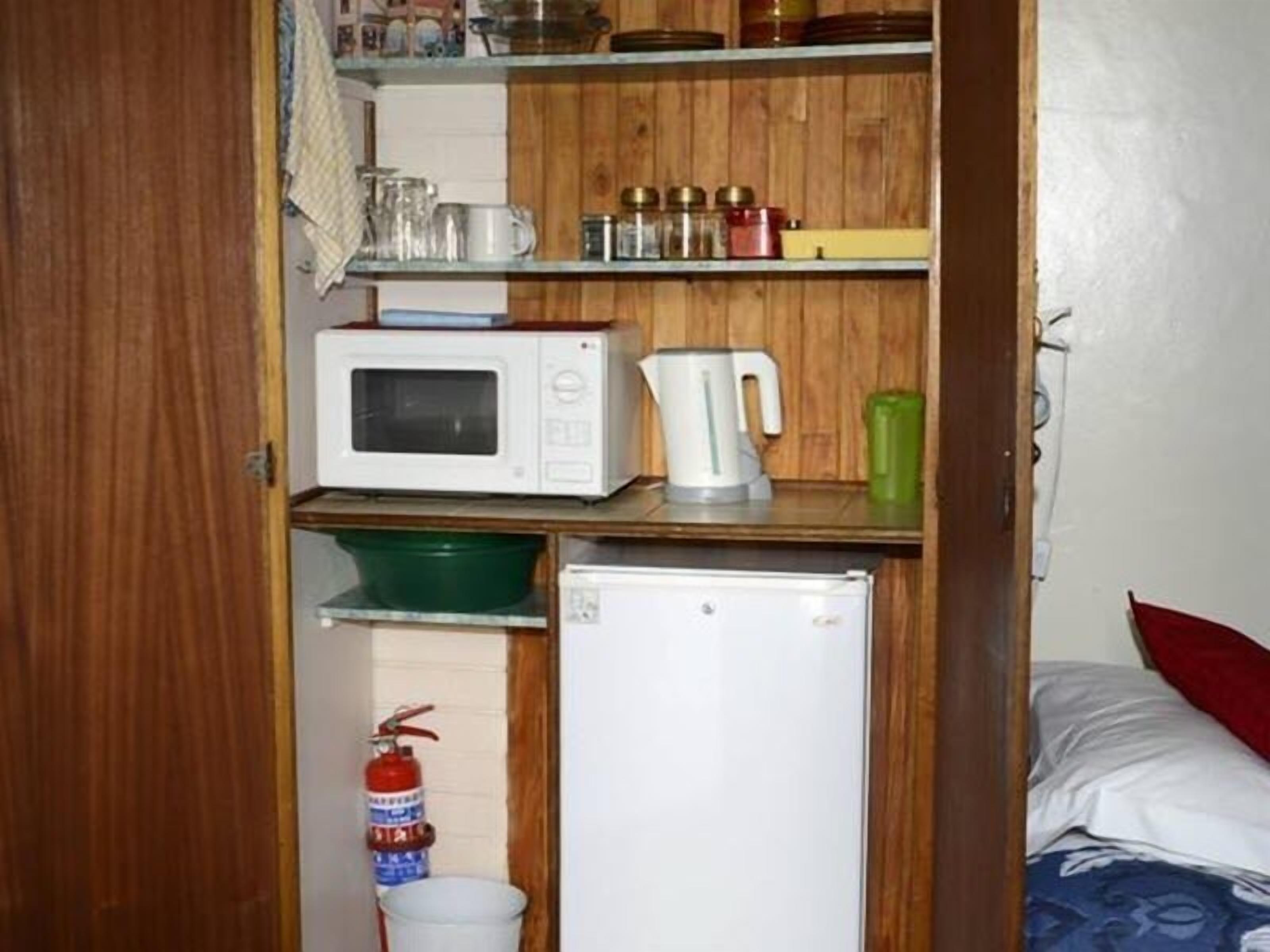 A compact kitchenette with a microwave, kettle, and small refrigerator.