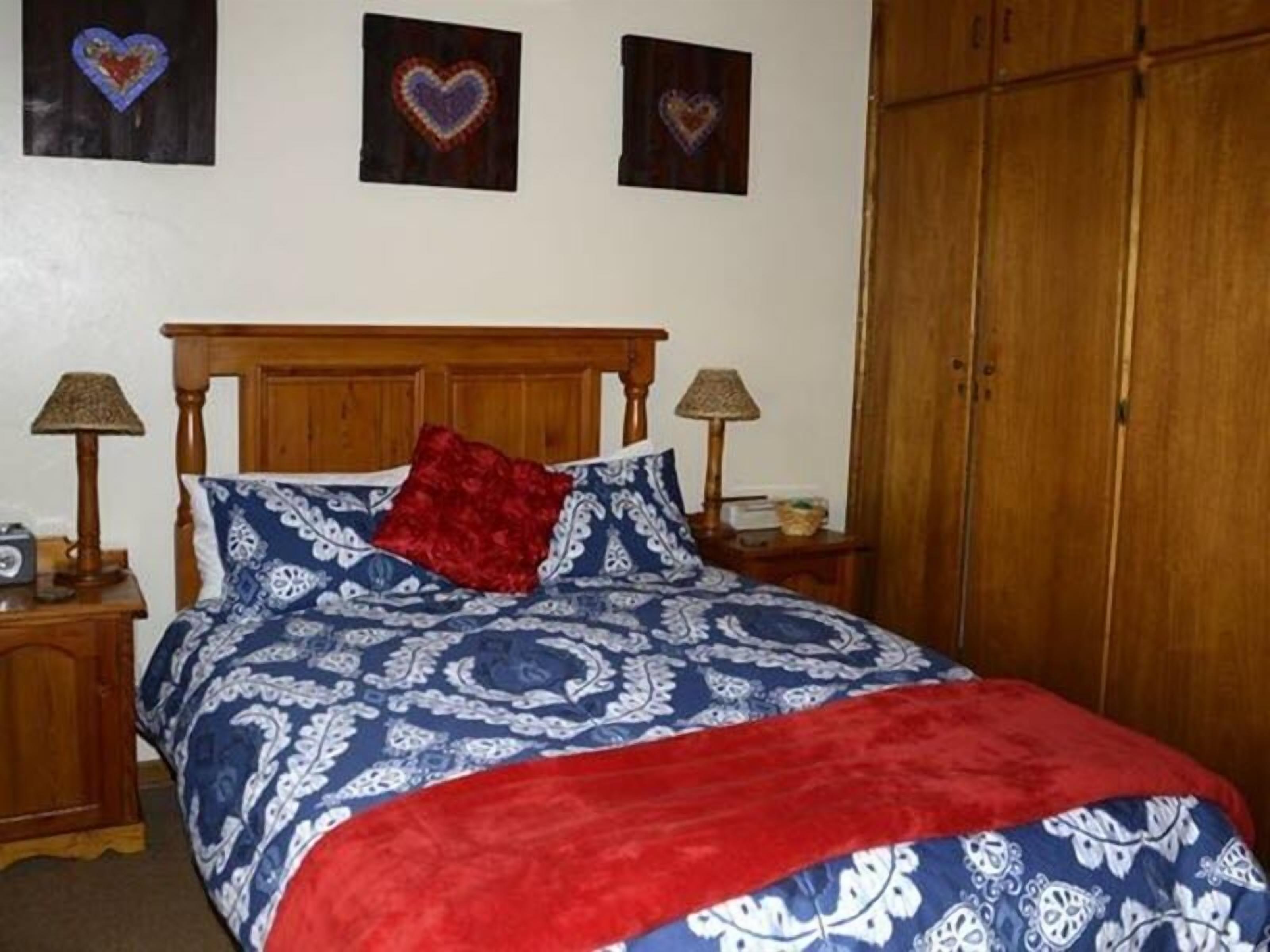 Ein Schlafzimmer mit einem hölzernen Bett, gemustertem Bettzeug, zwei Nachttischlampen und einem Kleiderschrank.