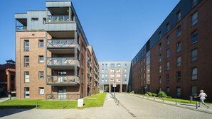 Un bâtiment moderne à plusieurs étages, doté de balcons et d’une cour intérieure.