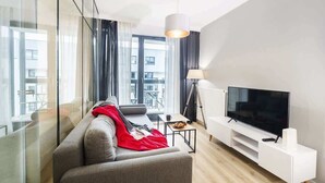 Un salon moderne avec un canapé, un téléviseur et une lampe.
