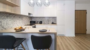 Une cuisine moderne dotée d’un îlot central, de luminaires suspendus et d’un revêtement mural décoratif.