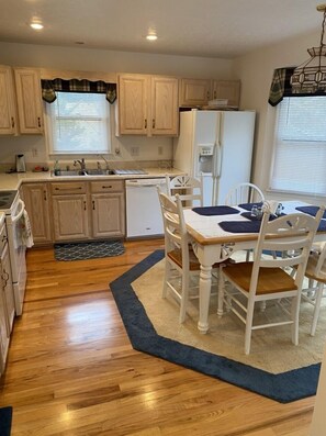 Compact kitchen with dining area, featuring a small dining table and chairs, sink, and refrigerator.