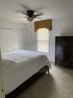 Enjoy a comfortable stay in this cozy room featuring a single bed, dresser, and ceiling fan.