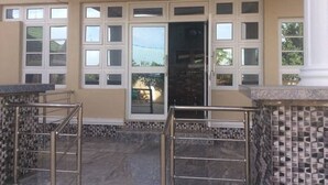 Zona de recepció amb un cartell, un sòl de rajoles i una porta de vidre que dona a l'interior.