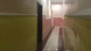 Un passadís estret amb una catifes vermella que condueix a una porta al final. Les parets tenen un color clar, i el sostre disposa d'il·luminació empotrada.