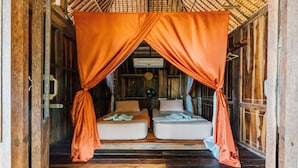 A room with two beds, wooden flooring, and a thatched roof. - LooLa Adventure Resort (Bintan)