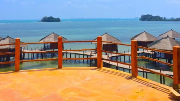A resort with wooden deck and thatched-roof structures overlooking a calm sea. - LooLa Adventure Resort (Bintan)