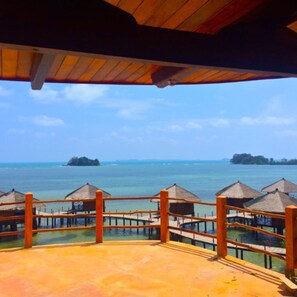 A resort with wooden deck and thatched-roof structures overlooking a calm sea. - LooLa Adventure Resort (Bintan)