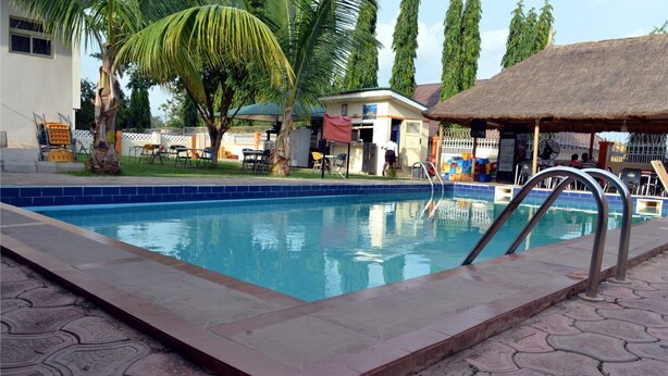 Una piscina amb una escala metàl·lica, envoltada d'un passeig tapat amb rajoles.