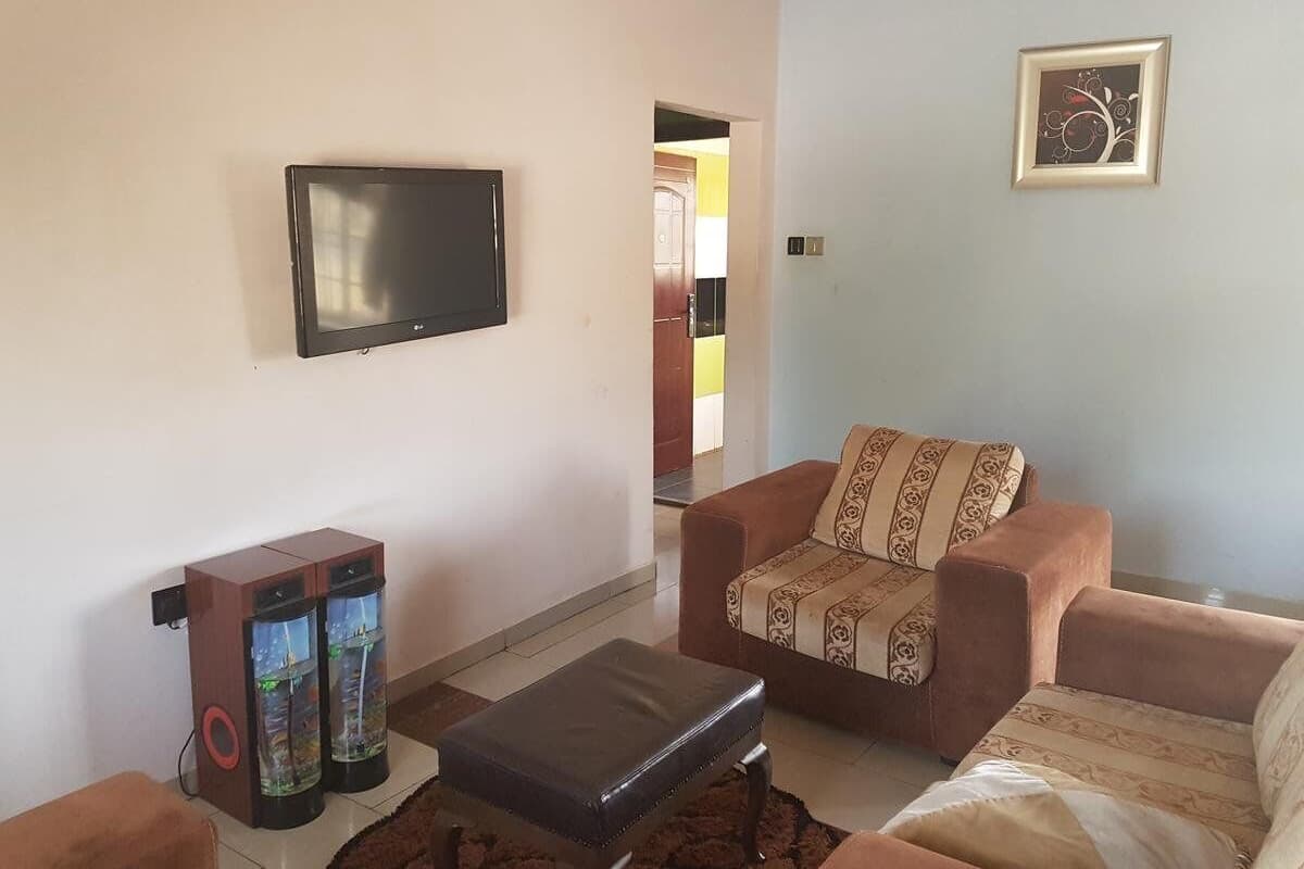 A living room with a flat-screen TV, two fish tanks, a brown sofa, and a patterned throw pillow.