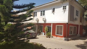 Edifici de dos pisos amb façana vermella i blanca, un carrer d'accés pavimentat i un cotxe estacionat.