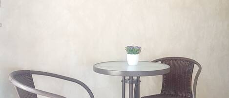 A wall-mounted TV above two wicker chairs and a small table with a potted plant.