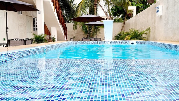 A clear blue mosaic pool with a wooden staircase leading up to a white door. - Casa Chujuk by Spirit Group (Isla Holbox)