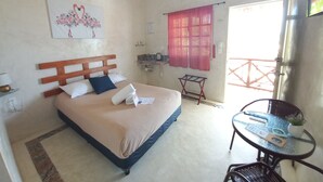 A bedroom with a bed, a small table, a chair, a window with curtains, and a wall-mounted air conditioner. - Casa Chujuk by Spirit Group (Isla Holbox)