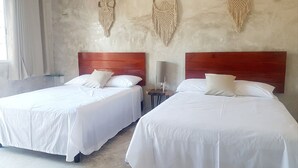 A hotel room with two beds, wooden headboards, white bedding, and macramé wall hangings. - Casa Chujuk by Spirit Group (Isla Holbox)
