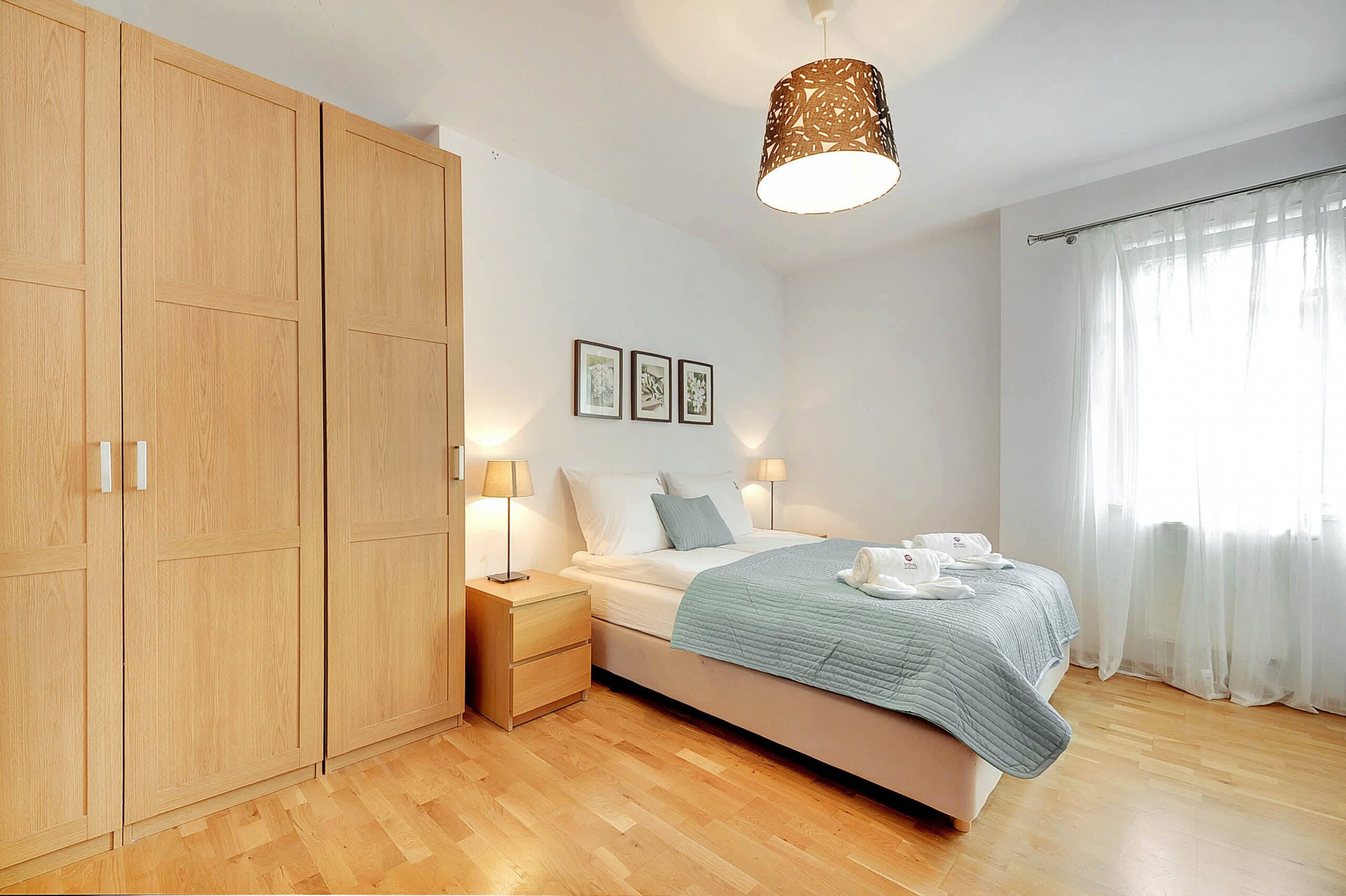 Een slaapkamer met een bed, nachtkastjes, een kledingkast en een hanglamp.