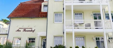 A multi-story hotel with a red-tiled roof, balconies, and a sign reading 'Ferienwohnungen Am Rosenhof'.