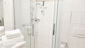 Ett modernt badrum med en dusch som är avskärmad med glasväggar, en toalett och en tvättställsdel.