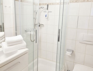 Un bagno moderno con cabina doccia in vetro, un water e un angolo lavabo.