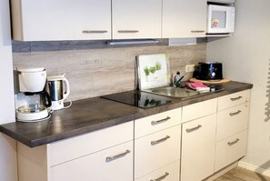 A kitchenette with a coffee maker, a kettle, a microwave, and a toaster on the counter.