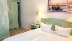 Une chambre d’hôtel avec un lit, une table de chevet, une lampe, un tableau et une armoire.