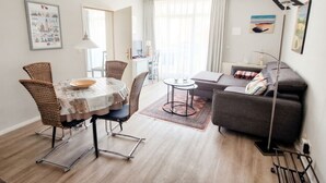Un salon moderne comprenant un coin repas, un canapé gris et un téléviseur à écran plat.