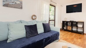 Un salón con sofá, televisión y suelo de madera.