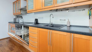 Una cocina compacta con armarios de madera, lavavajillas integrado, microondas y fregadero.