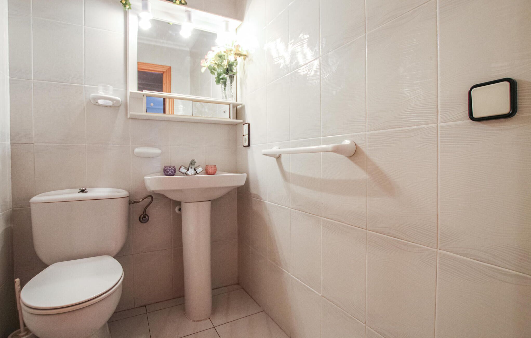 Een kleine badkamer met toilet, wastafel en spiegel.
