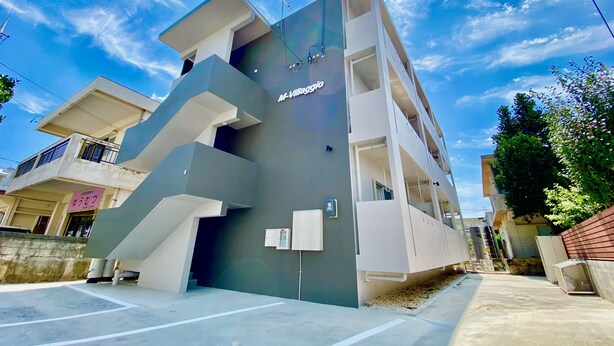 Un immeuble moderne à plusieurs étages, doté d’un toit plat et d’une enseigne indiquant « M-Village ».