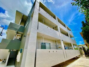 A multi-story building with balconies, a staircase, and a visible ground floor entrance.