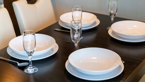 Et spisebord dækket med hvide tallerkener, klare glas og et stearinlys.