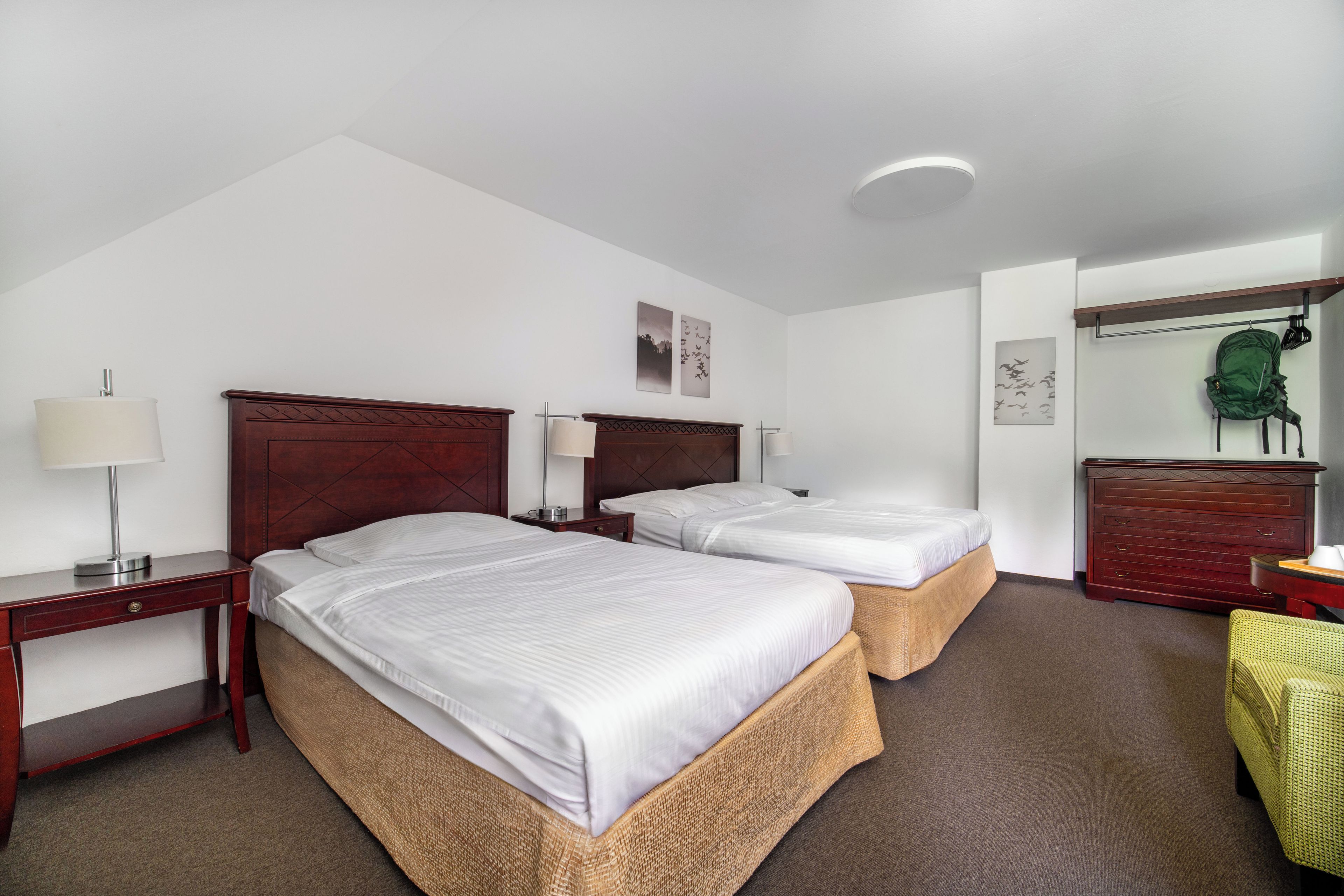 A hotel room with two beds, a desk, a chair, and a wardrobe.