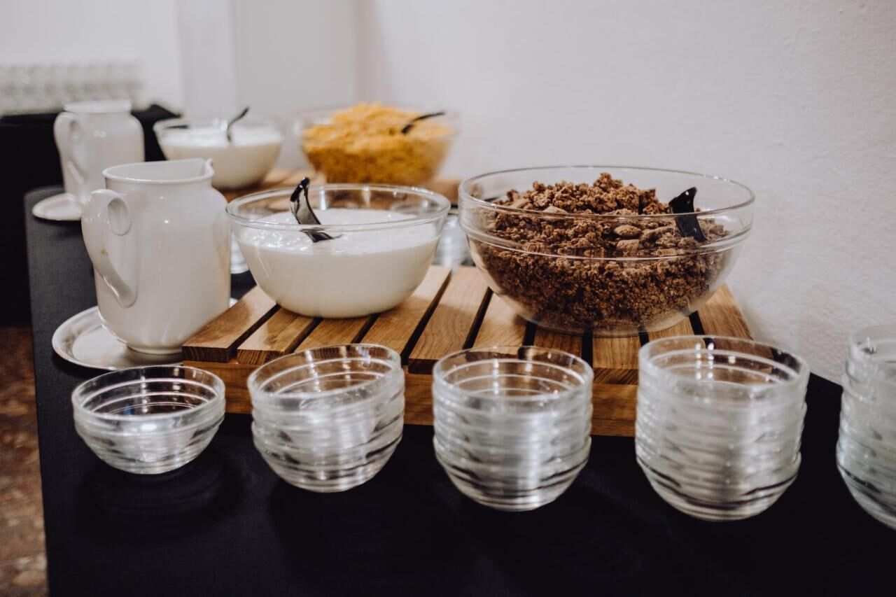 A breakfast setup with a pitcher, bowl, and glasses on a wooden board.