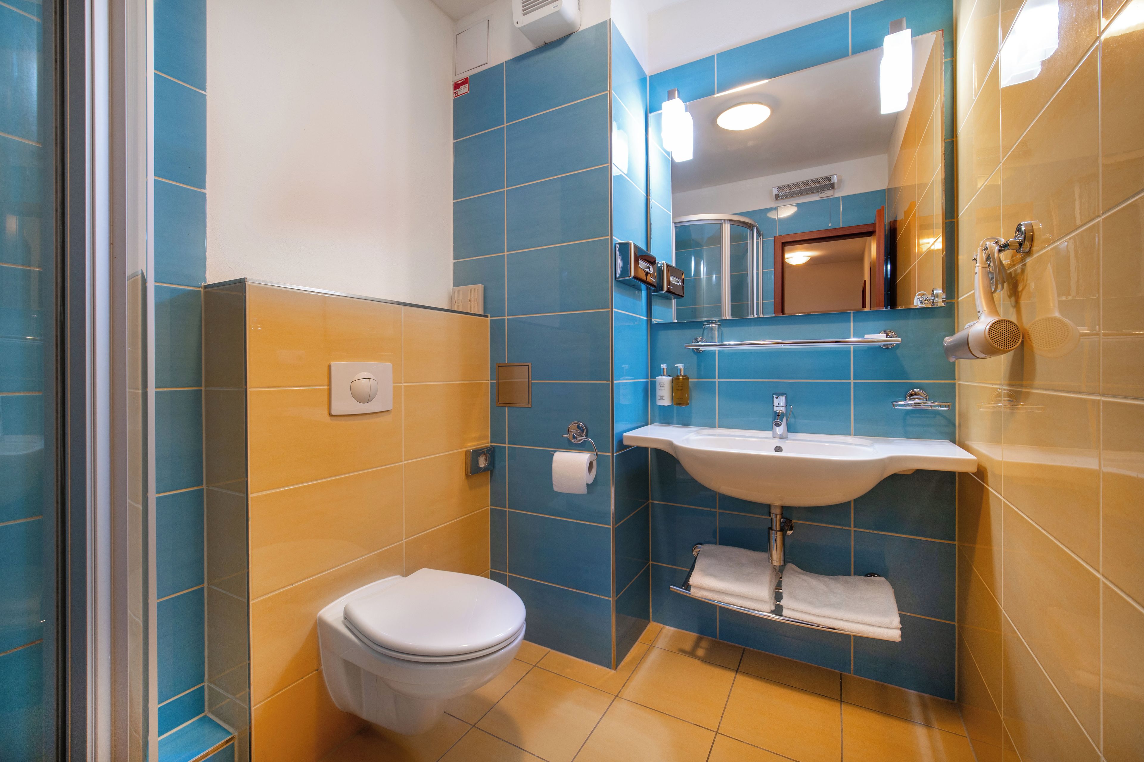 A bathroom with a toilet, sink, and mirror.