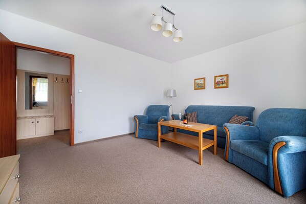 A modern living room with a sofa set, a wooden coffee table, and a lamp. - Hotel Petrovy kameny (Loucna nad Desnou)
