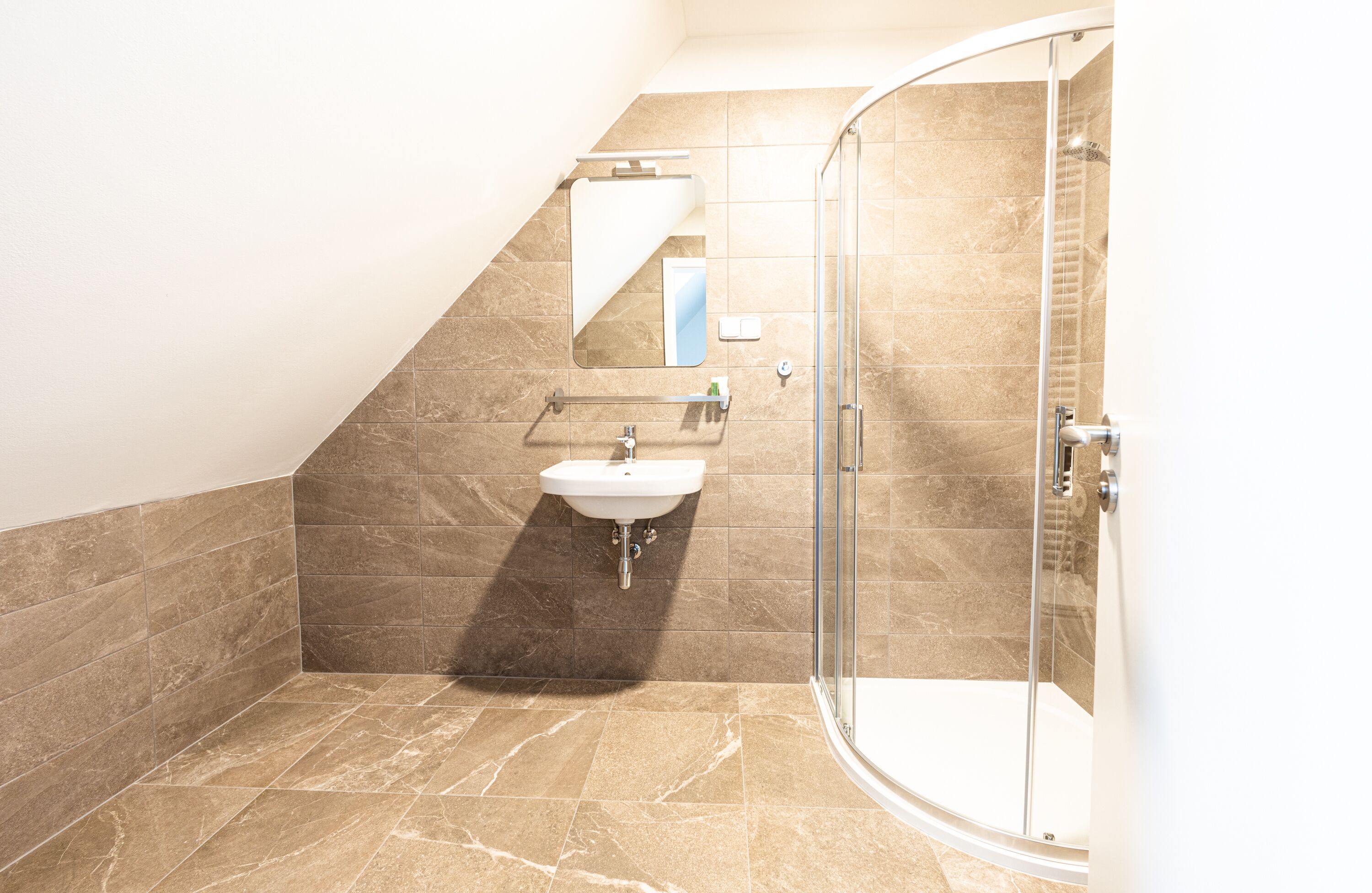 Un baño con cabina de ducha de vidrio, un lavabo y un espejo.
