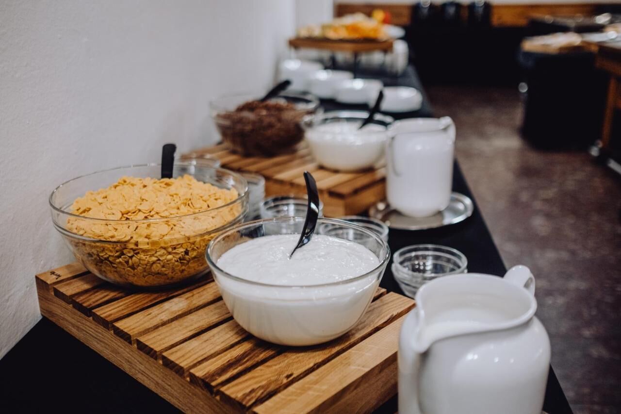 A buffet setup with various food items and serving utensils on wooden tables.