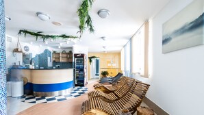 Moderni aula, jossa on ruutukuviollinen lattia, vastaanottotiski, puinen penkki ja suuri ikkuna.