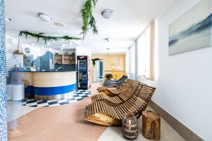 Un vestíbulo moderno con piso a cuadros, un mostrador de recepción, un banco de madera y un ventanal grande.