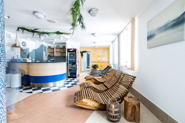 A modern lobby with a checkered floor, a reception desk, a wooden bench, and a large window. - Hotel Petrovy kameny (Loucna nad Desnou)