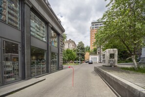A street view with a modern building on the left, a tree-lined sidewalk, and a tram on the right. - Scandinavian Apartments (Kyiv)