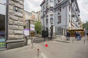A stone building with a metal gate, a signboard, and a red arrow pointing to the right. - Scandinavian Apartments (Kyiv)