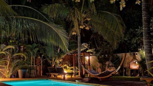 A nighttime pool area with a hammock, lounge chairs, and a wooden deck. - Bougainvillier, pool, direct access to the beach (Grand Fond)