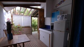 A kitchen with a microwave, a sink, and a refrigerator. There is a wooden table and chairs, and a potted plant. - Bougainvillier, pool, direct access to the beach (Grand Fond)