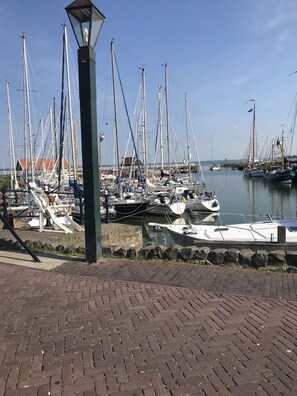 A marina with multiple sailboats docked, a brick-paved walkway, and a lamp post. - Enjoy a luxury holiday home, close to the IJsselmeer and beach (Warns)